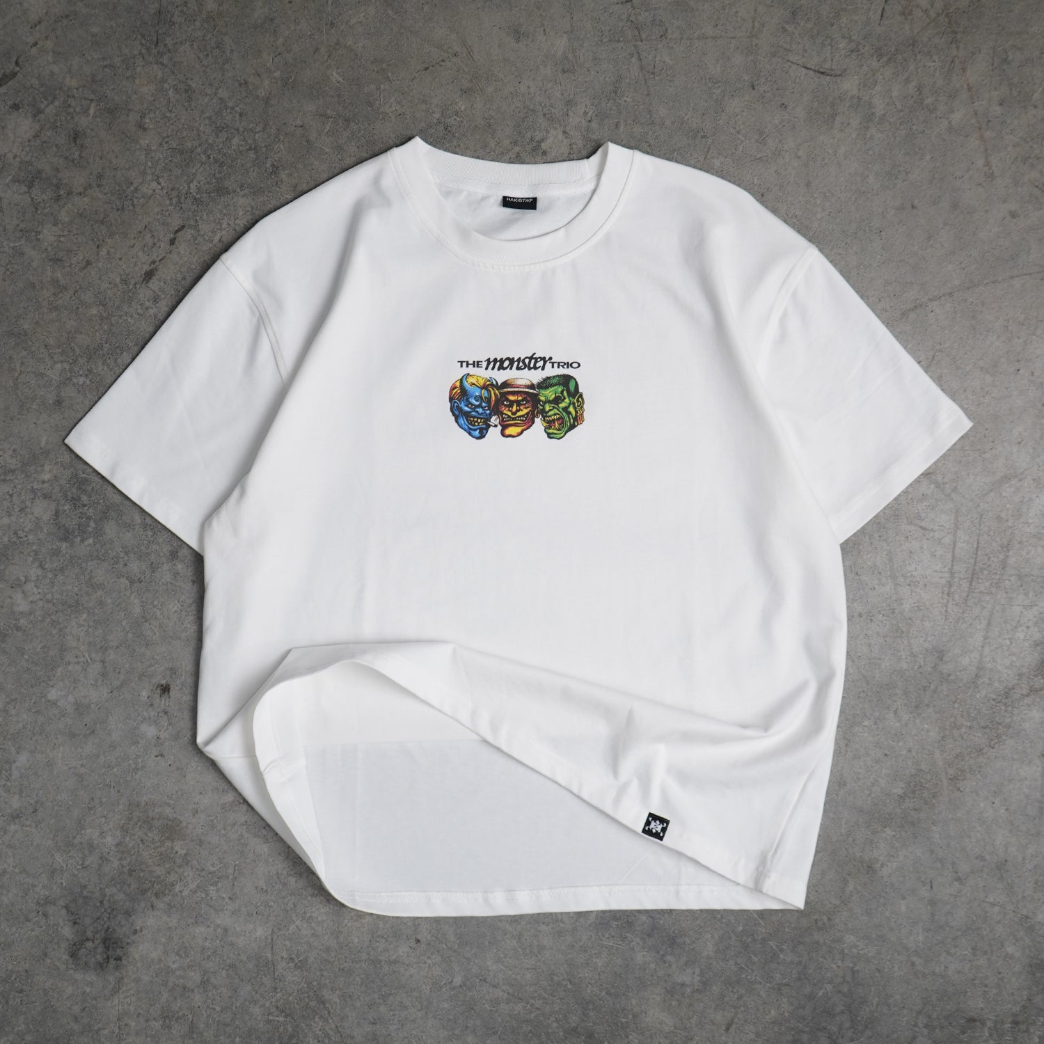 White t-shirt with colorful graphic design on a gray concrete surface
