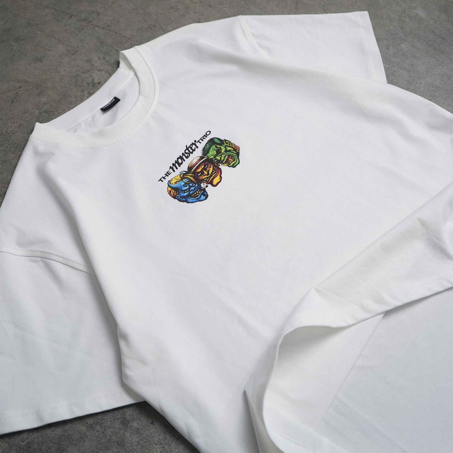 White sweatshirt with colorful graphic design on a gray surface