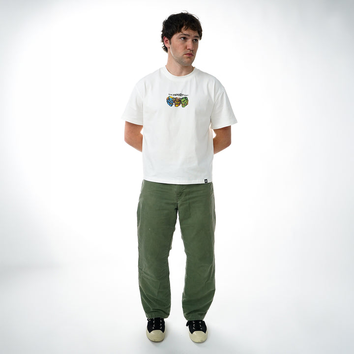 Man wearing a white t-shirt with a graphic design and green pants on a white background