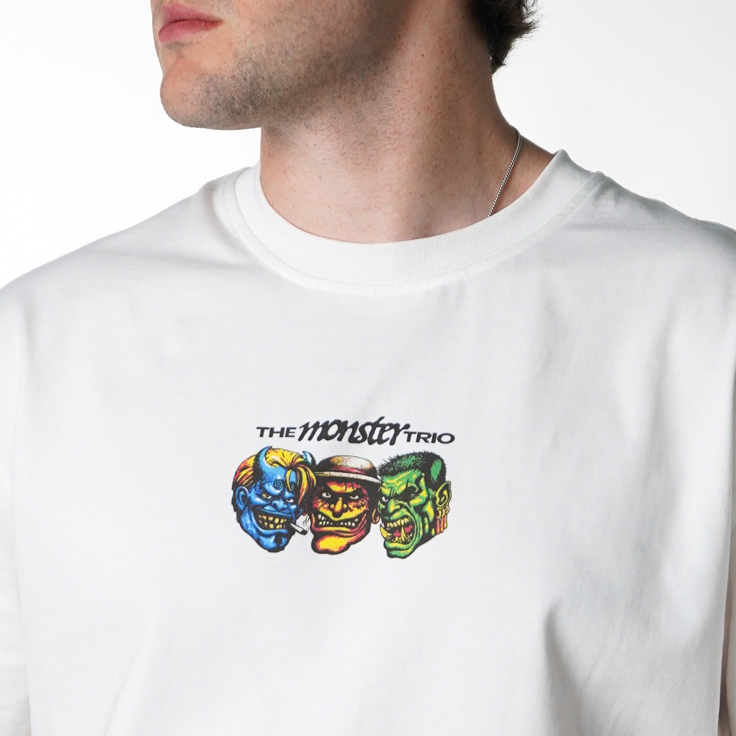 White t-shirt with colorful monster graphic and 'The Monster Trio' text on a white background
