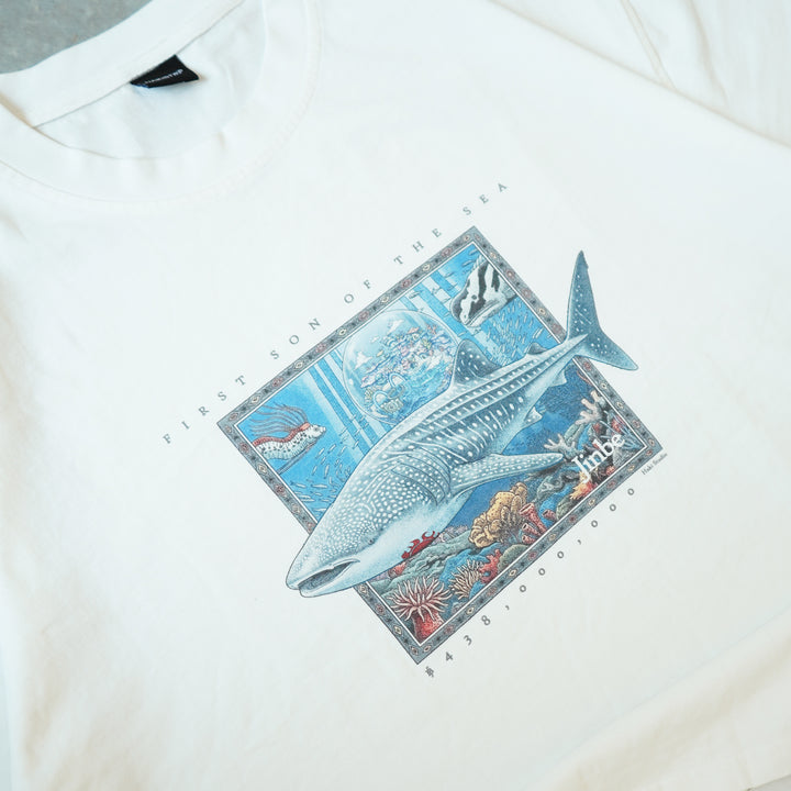 White shirt with a whale and ocean scene graphic on a white background