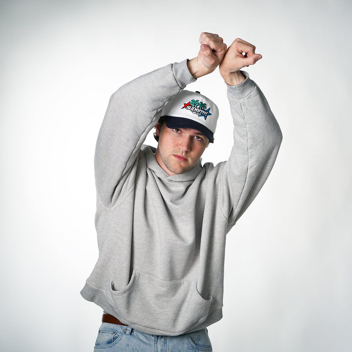 Person wearing a gray hoodie and a cap with a logo on a white background