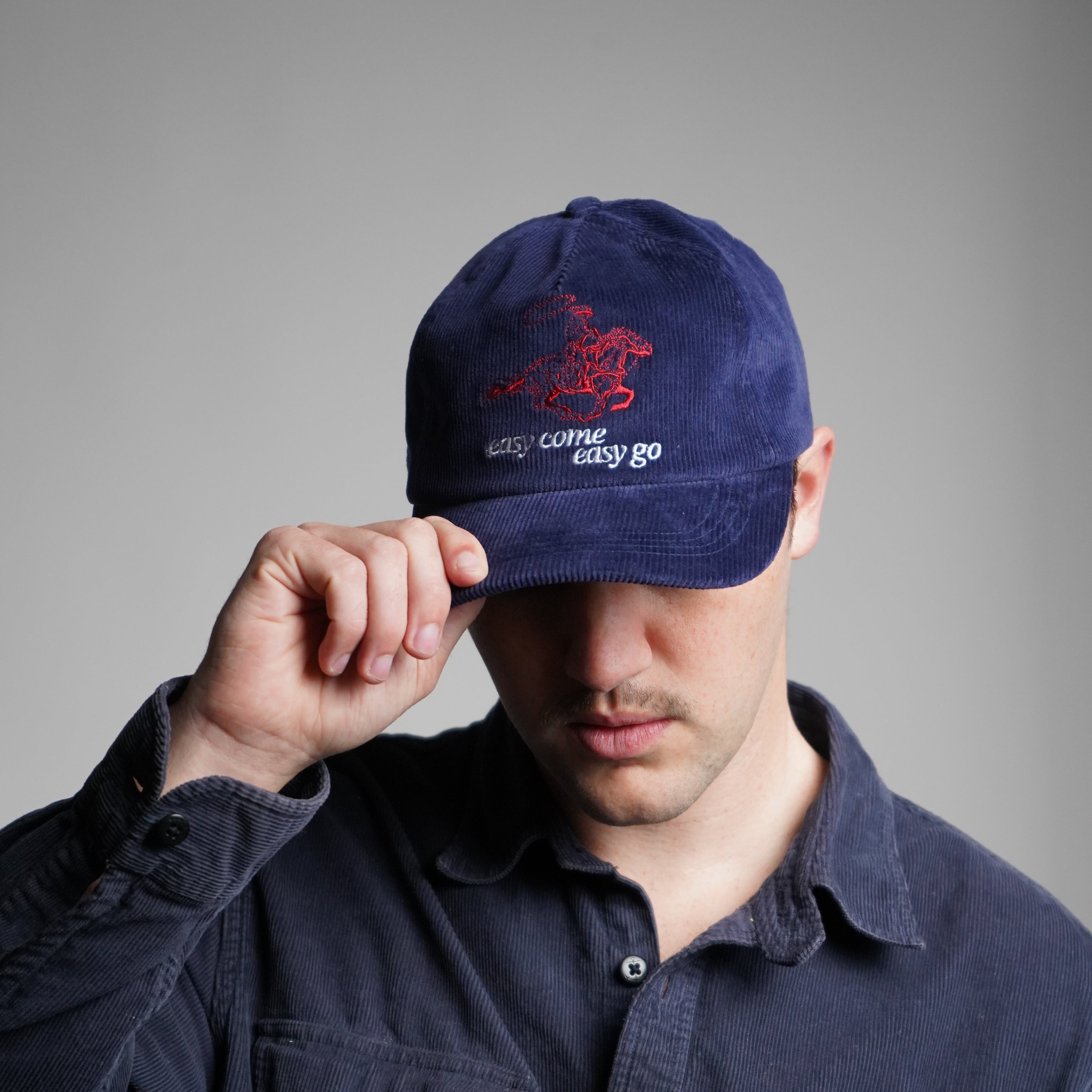 Person wearing a navy blue cap with a logo on a gray background