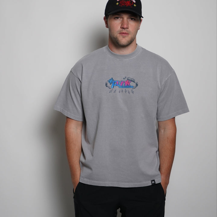 Person wearing a gray t-shirt with a logo and a black cap on a plain background