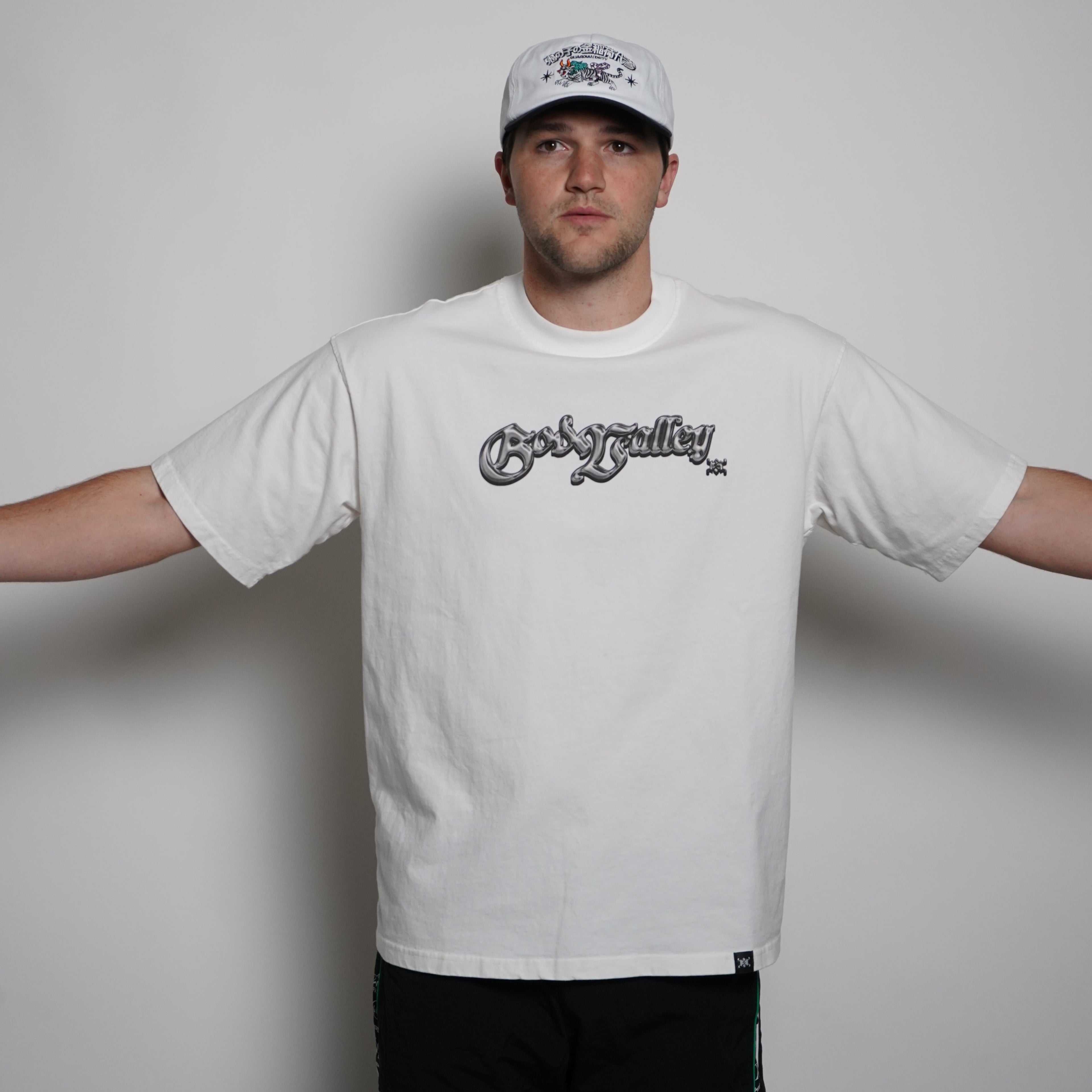 Person wearing a white t-shirt with a logo on a plain background