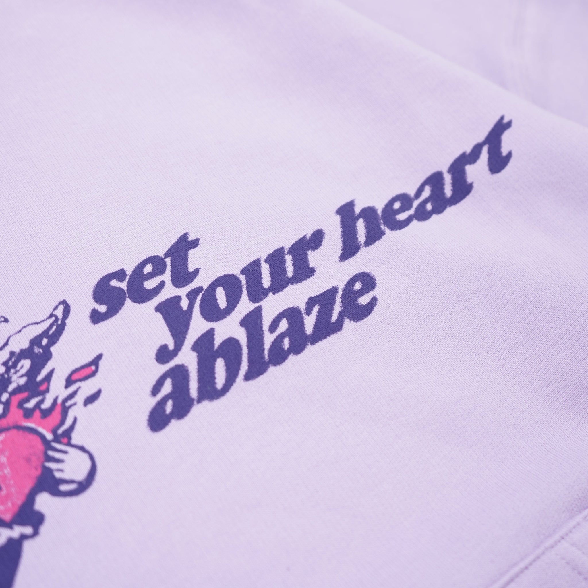 Purple hoodie with text 'set your heart ablaze' on a light purple background