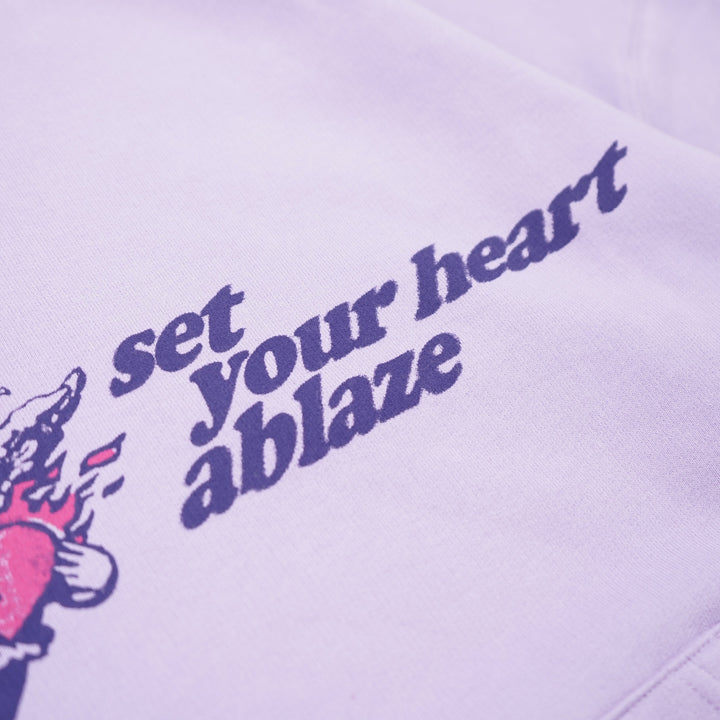 Purple hoodie with text 'set your heart ablaze' on a light purple background