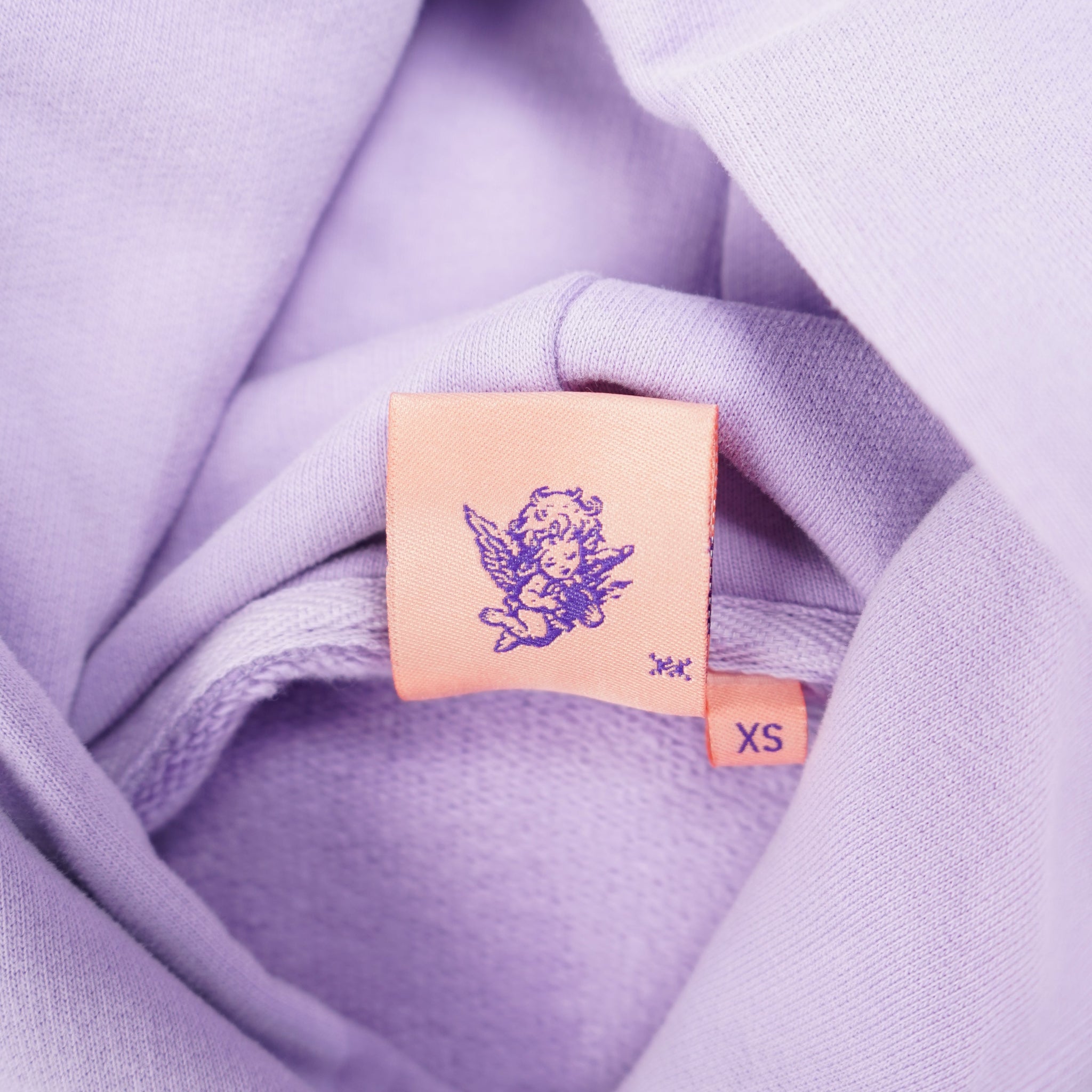 Close-up of a lavender fabric with a small rectangular tag featuring a logo.