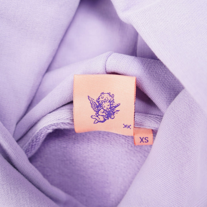Close-up of a lavender fabric with a small rectangular tag featuring a logo.