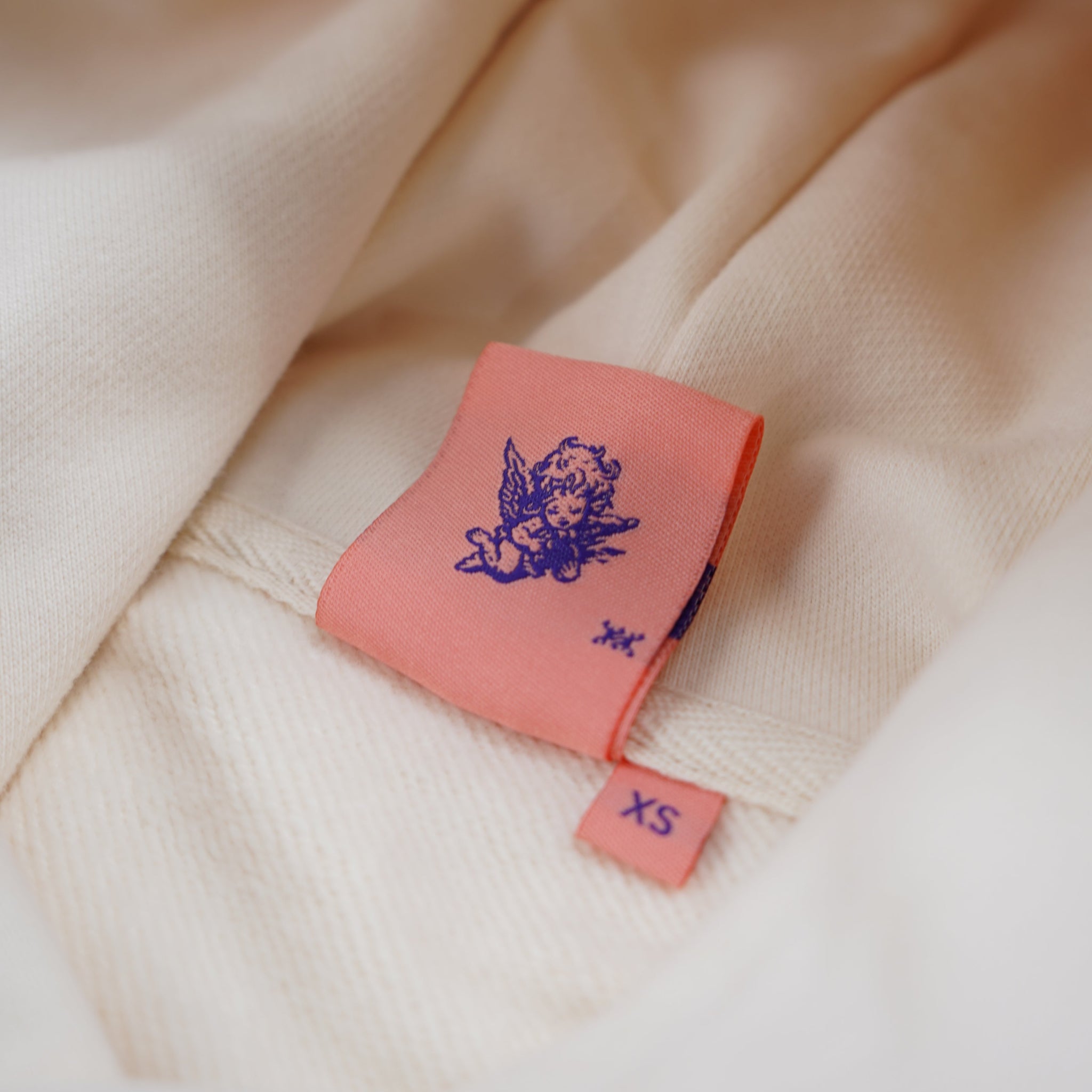 Close-up of a pink label with a logo on a beige fabric background