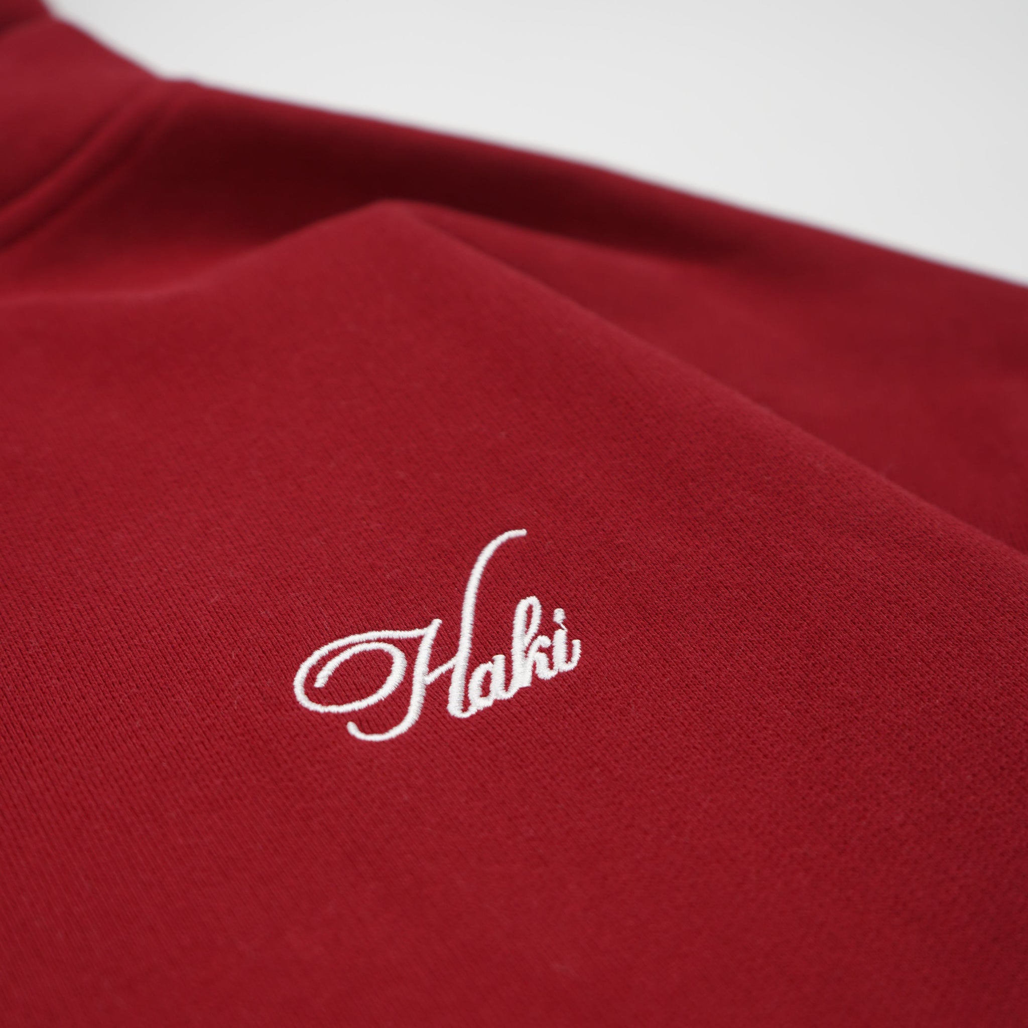 Red garment with white embroidered logo on a white background