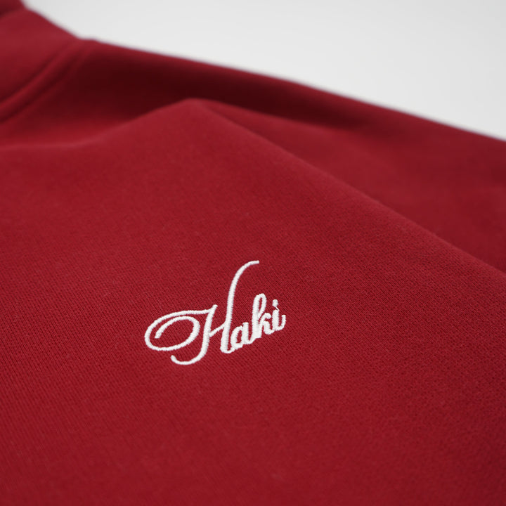 Red garment with white embroidered logo on a white background