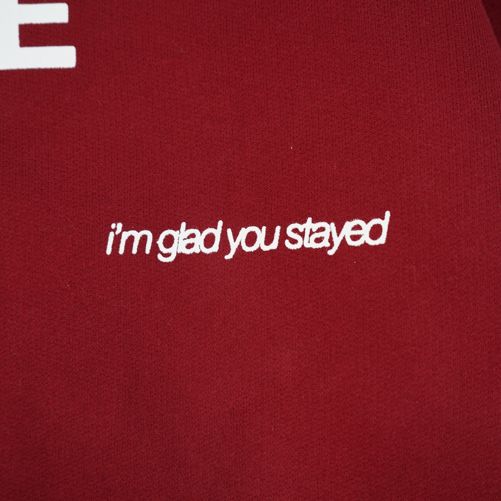 Red fabric with white text 'i'm glad you stayed' and partially visible brand name.