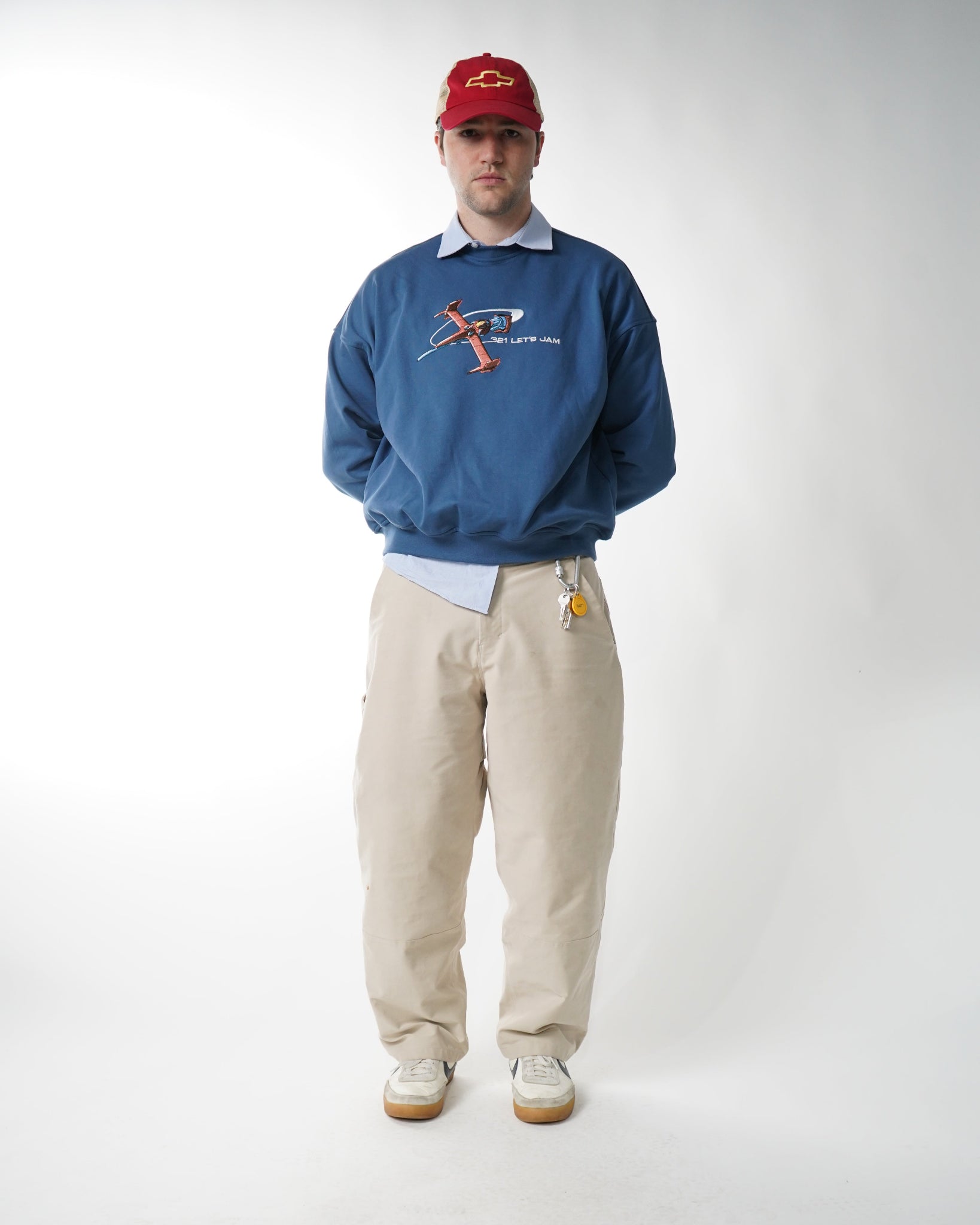 Person wearing a blue hoodie and beige pants on a white background