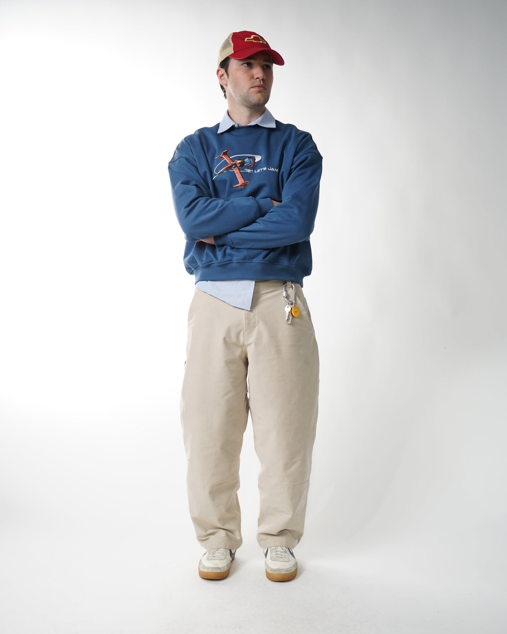Person wearing a blue jacket, beige pants, and a red cap on a white background
