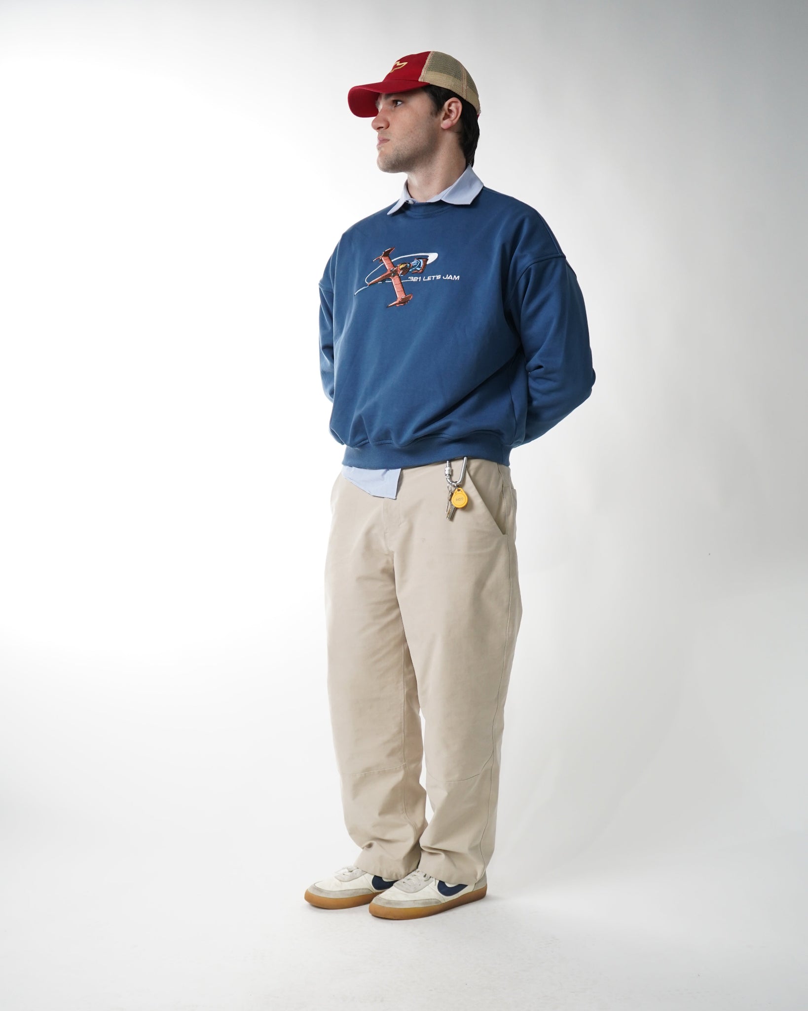 Person wearing a blue jacket and beige pants on a white background