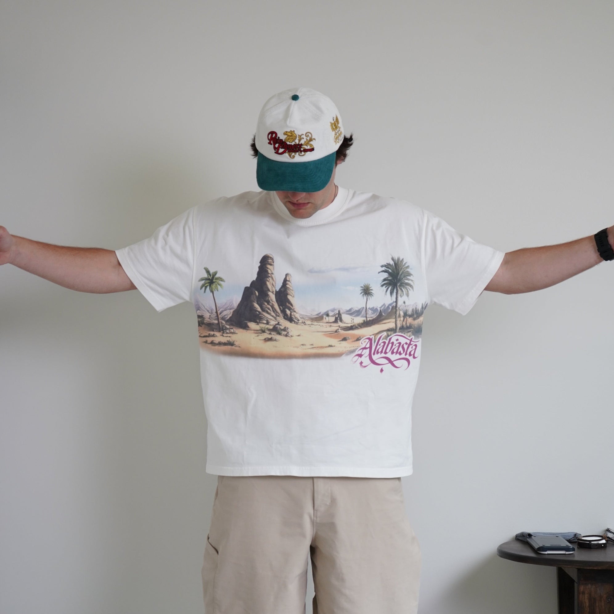 Person wearing a graphic t-shirt and beige pants standing on a white floor.